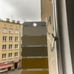 Przytulny salon pomalowany na kolor ral 8003 - gliniastożółty, z dodatkami w odcieniach beżu i drewna.
